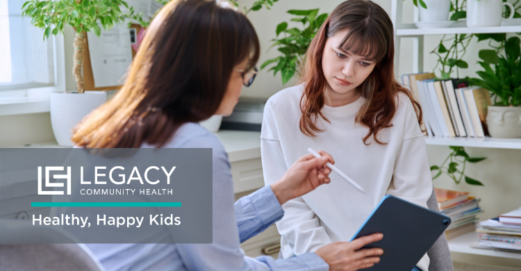 Healthcare professional discusses with a young woman in a bright office; clipboard and tablet present, Legacy Community Health logo shown with 'Healthy, Happy Kids' tagline.
