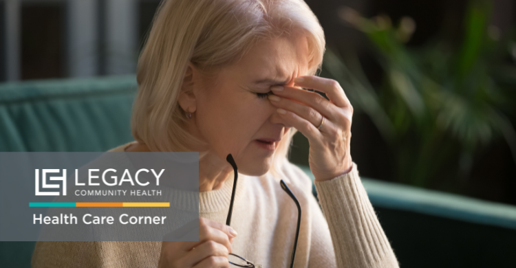Older woman pinching her temple in discomfort, holding glasses, with a Legacy Health logo and 'Health Care Corner' overlay nearby.