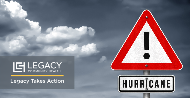 Hurricane warning sign with 'HURRICANE' label beside a Legacy Community Health logo and cloudy sky, signaling action.