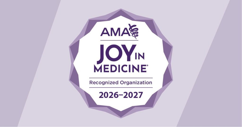Badge displaying the logo and text: "AMA Joy in Medicine Recognized Organization 2026-2027." The badge is set against a purple background with a ribbon featuring the Rod of Asclepius symbol.