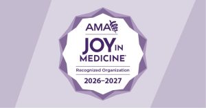 Badge displaying the logo and text: "AMA Joy in Medicine Recognized Organization 2026-2027." The badge is set against a purple background with a ribbon featuring the Rod of Asclepius symbol.